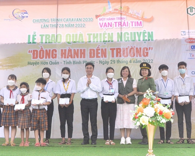 Giám đốc TT XTĐTTM&DL tỉnh Bình Phước Trần Quốc Duy (chính giữa) và Phó Chủ tịch CLB Doanh nhân 2030 Hà Lê Thùy Quyên (thứ 4, phải sang) trao học bổng cho thiếu nhi huyện Hớn Quản.