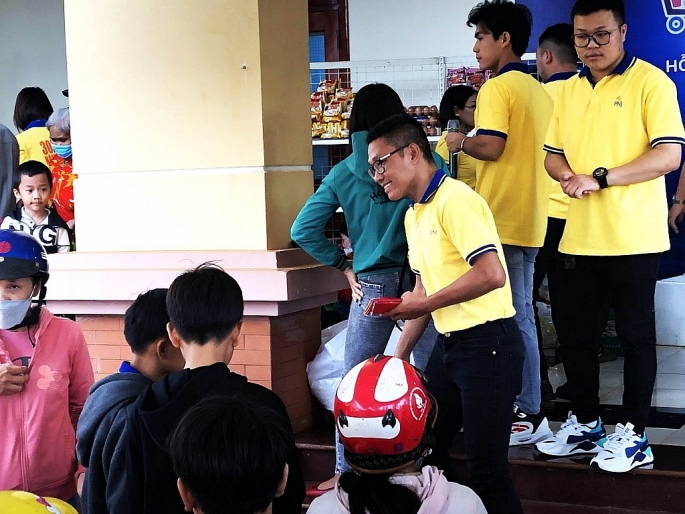 Anh Trương Hoàng Lâm, Quản lý kinh doanh khu vực Bình Dương - Bình Phước của PNJ trao phong bì lì xì cho trẻ em tham gia “Siêu thị mini Tết 0 đồng”.