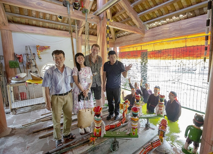 Ông Đặng Minh Hưng (Trưởng phường rối nước Đào Thục) giới thiệu cho du khách nước ngoài về nét văn hóa đặc sắc của nghệ thuật múa rối nước(ảnh: Văn Biên)