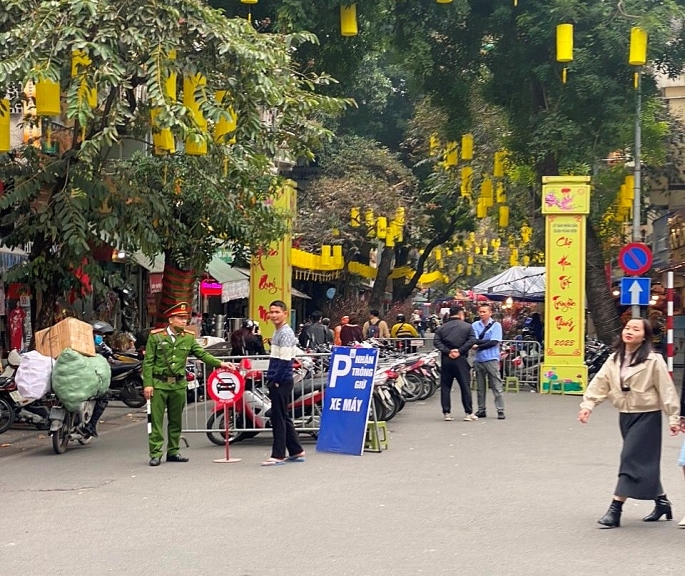 CBCS Công an phường Hàng Mã cắm chốt bảo đảm an toàn cho người dân tới mua sắm đồ trang trí Tết và tận hưởng không khí mùa xuân tại chợ hoa Hàng Lược.(ảnh: Văn Biên)