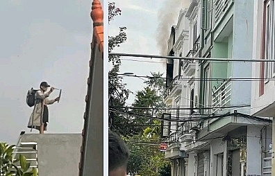 Đối tượng có biểu hiện ngáo đá đang đứng trên tầng tum ngôi nhà bị cháy