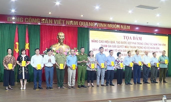 Chỉ huy công an quận Hà Đông trao sổ tay an ninh cho các Tổ hòa giải. Ảnh: Khánh Phong