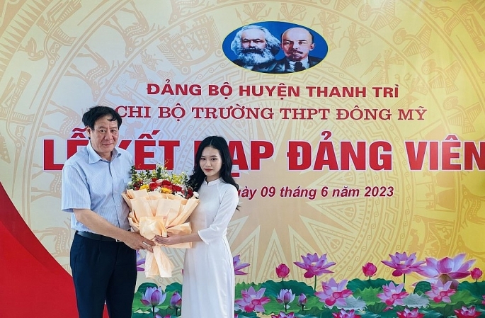 Đồng chí Lê Tiến Nhật, Thành uỷ viên, Bí thư Huyện uỷ Thanh Trì tặng hoa chúc mừng tân đảng viên Đặng Hà Giang.