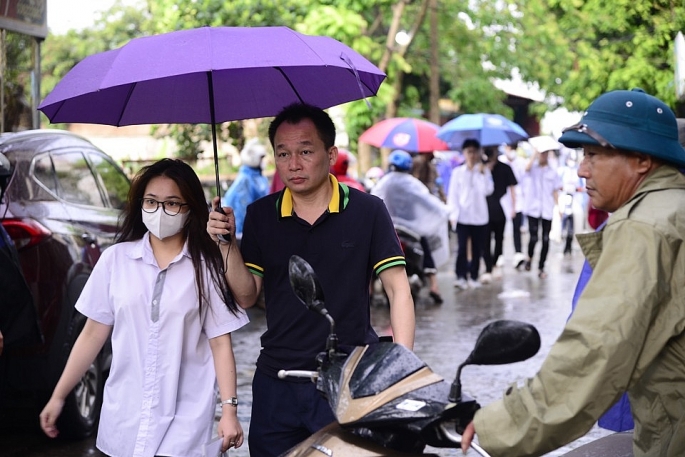 Tại khu vực huyện Mê Linh, nhiều phu huynh phải lách cách áo mưa, ô che đưa các sĩ tử đi thi (ảnh Phạm Hùng)