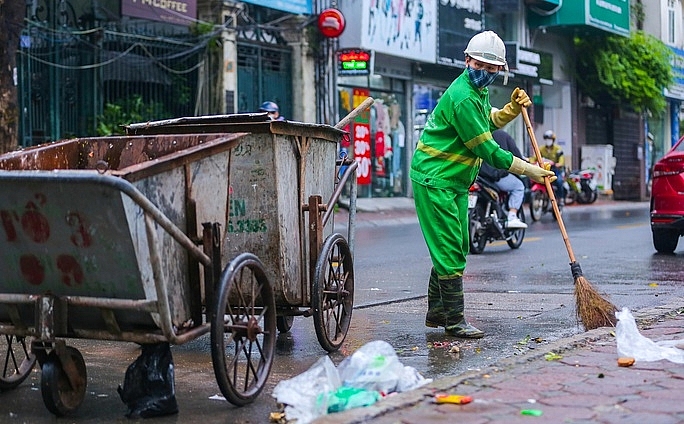 Công nhân đang thu dọn rác trên đường Nguyễn Khang, Cầu Giấy, Hà Nội. Ảnh: NLĐ