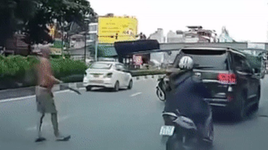 Người đàn ông cởi trần phi dao cắm vào kính ô tô Land Cruiser đang chạy trên đường phố Hà Nội