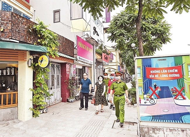 Cán bộ tổ dân phố 17 phường Khương Mai (quận Thanh Xuân) cùng cảnh sát khu vực nhắc nhở các cửa hàng kinh doanh bảo đảm trật tự đô thị. . Ảnh: Khải Lâm