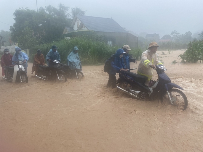 Nước dâng cao ở nhiều tuyến đường, lực lượng chức năng phải hỗ trợ người dân khi di chuyển qua khu vực ngập nước (ảnh Huy Hoàng)