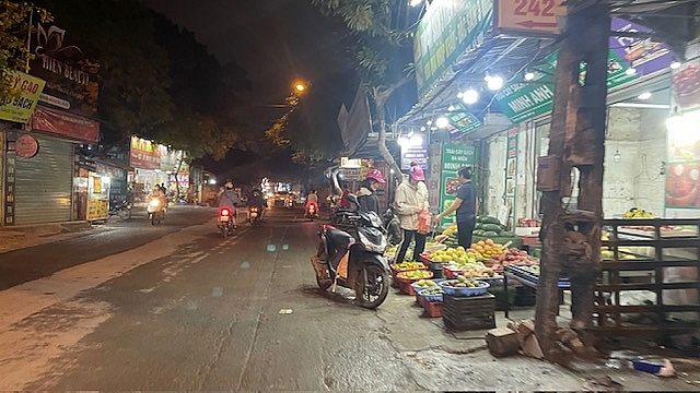 Một cửa hàng bán hoa quả bày hàng tràn kín phần vỉa hè, người mua phải dừng xe dưới lòng đường để mua hàng hóa, tại đường Lĩnh Nam, quận Hoàng Mai, Hà Nội	Ảnh: Duy Anh