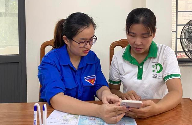 Thành viên Tổ công nghệ số cộng đồng xã Cự Khê, huyện Thanh Oai hướng dẫn công dân sử dụng dịch vụ công trực tuyến. Ảnh: Ánh Ngọc