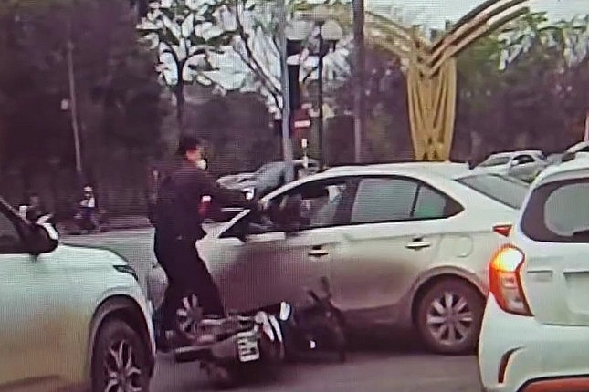 Hình ảnh người đàn ông đi xe máy cầm mũ bảo hiểm đập vỡ kính xe ô tô (Ảnh: cắt từ video)