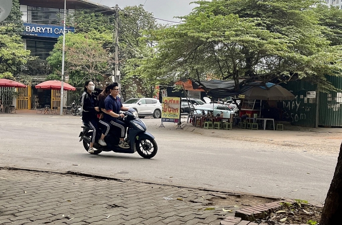 Hình ảnh học sinh điều khiển xe gắn máy không đội mũ bảo hiểm trên phố Đinh Núp, quận Cầu Giấy, Hà Nội.	Ảnh: Minh Dương
