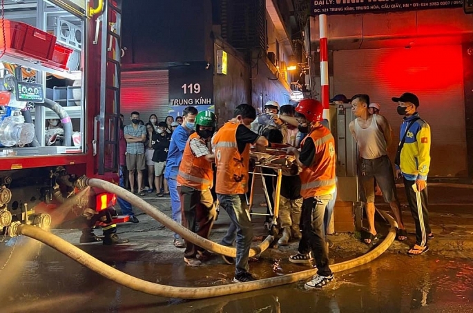 Lực lượng chức năng đưa nạn nhân ra khỏi ngôi nhà cháy, đưa đến cơ sở y tế - Ảnh: Tuấn Sơn