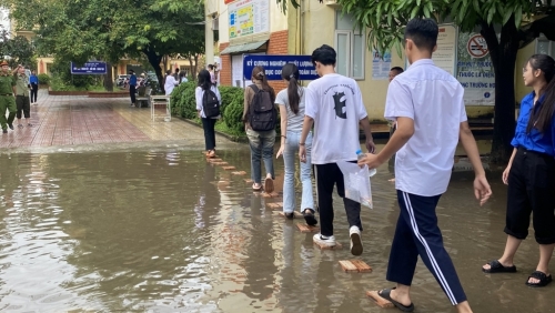 Cổng trường bị ngập nước, thanh niên tình nguyện "xếp" đường cho thí sinh di chuyển vào phòng thi