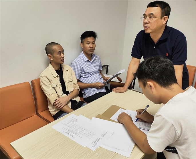 INTERPOL Việt Nam tiến hành thủ tục bàn giao đối tượng Đặng Quốc Huy (áo vàng) cho Công an tỉnh Bắc Giang. Ảnh: CQCA