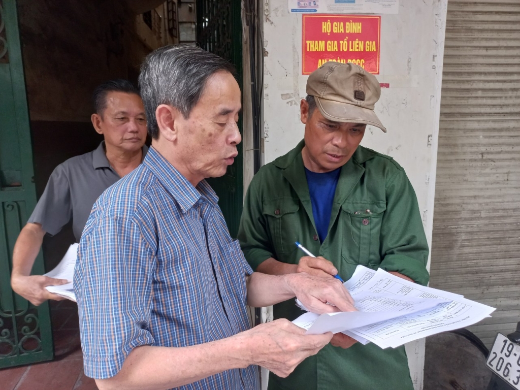 Ông Đặng Văn Long - Tổ trưởng Tổ dân phố số 2 phường Hàng Bồ (đứng bên phải) tuyên truyền tới người dân về quy định phân loại rác tại nguồn    Ảnh: MỘC MIÊN