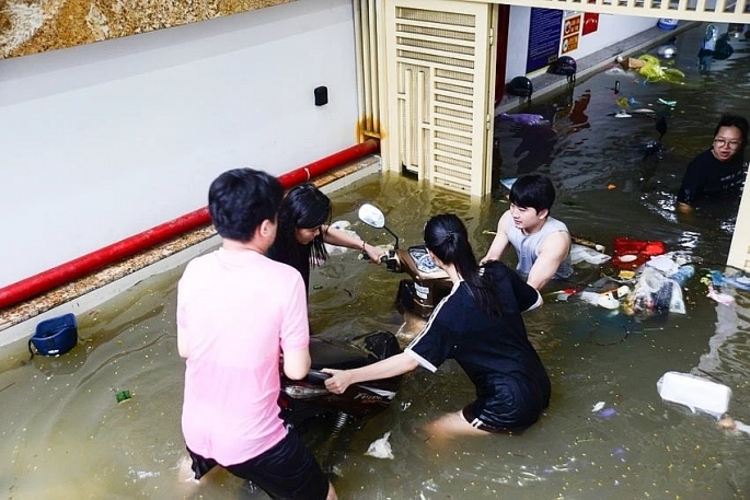 Sau trận mưa lớn tối ngày 23/7, nhiều người đã phải dầm mình xuống nước để để đưa xe máy bị kẹt trong hầm xe chung cư ra ngoài (Ảnh: Phi Hùng)