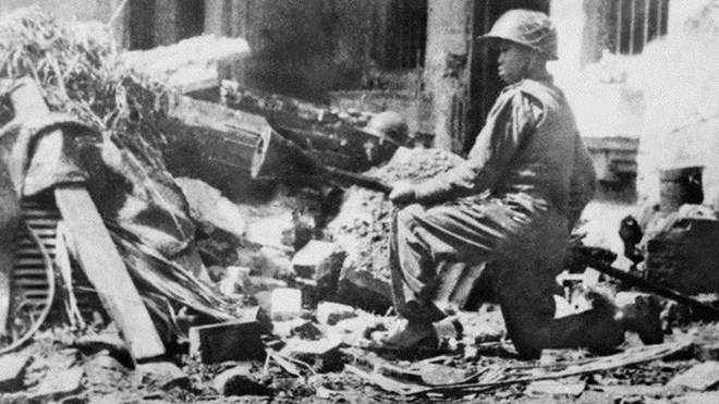 Chiến sĩ cảm tử Liên khu I Nguyễn Văn Thiềng ôm bom ba càng chặn chiến xa Pháp tại phố Hàng Đậu tháng 12/1946. Ảnh: TTXVN