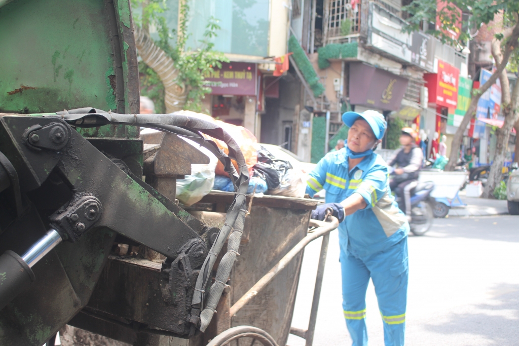 Gần 12h trưa, cô Trần Thị Mai Loan và các công nhân vệ sinh môi trường vẫn làm việc thu gom rác thải. Ảnh: Mộc Miên