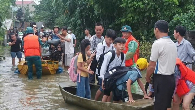 Lực lượng chức năng và người dân hỗ trợ đưa học sinh qua khu ngập để đến trường. Ảnh: N.M.