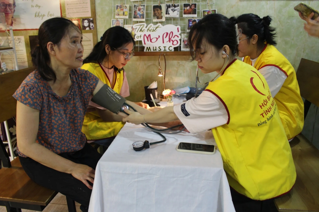 Các sinh viên tình nguyện tham gia hỗ trợ đo huyết áp cho người dân đến khám bệnh tại quán cà phê Mơ Phố. Ảnh: Mộc Miên