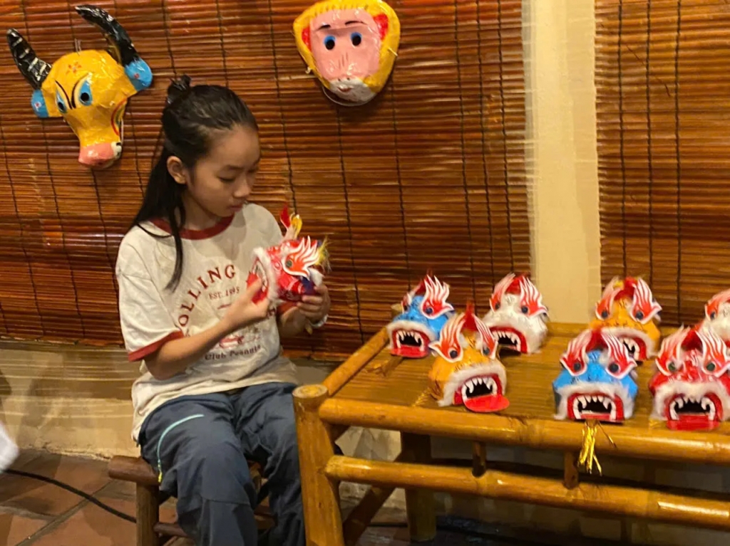 Em nhỏ chăm chú quan sát mô hình đầu sư tử tại đình Kim Ngân. Ảnh: An Nhiên