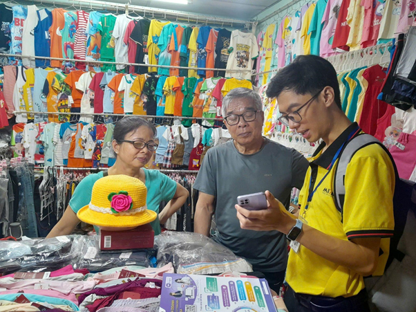 Nhân viên MISA (áo vàng) hỗ trợ trực tiếp cho các hộ kinh doanh cài đặt, sử dụng phần mềm MISA eShop để bán hàng, xuất hóa đơn, kê khai thuế tại chợ