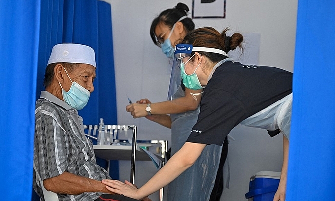 Nhân viên y tế đang trấn an tinh thần cho người dân trước khi tiêm vaccine ngừa Covid-19 tại thủ đô Kuala Lumpur, Malaysia. (Ảnh: AFP)