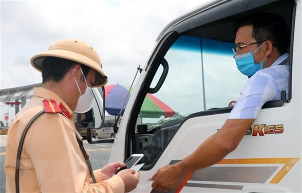 Cảnh sát giao thông kiểm tra giấy tờ của một phương tiện chở hàng hóa ngay tại chốt kiểm soát dịch COVID-19. (Ảnh: Minh Sơn/Vietnam+)