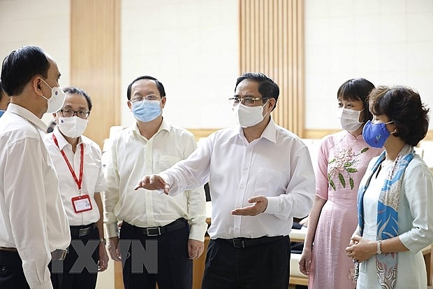 Thủ tướng Phạm Minh Chính trao đổi với các đơn vị nghiên cứu, sản xuất vaccine phòng COVID-19 trong nước. (Ảnh: Dương Giang/TTXVN)