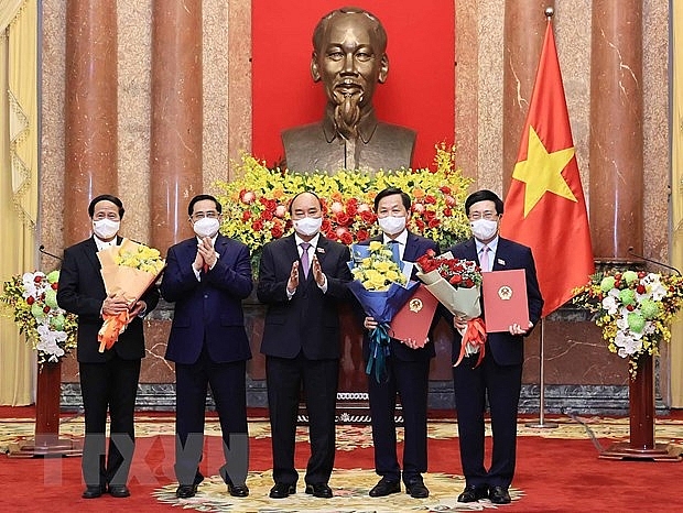 Chủ tịch nước Nguyễn Xuân Phúc trao Quyết định, Thủ tướng Phạm Minh Chính tặng hoa cho các Phó Thủ tướng Chính phủ. (Ảnh: Thống Nhất/TTXVN)