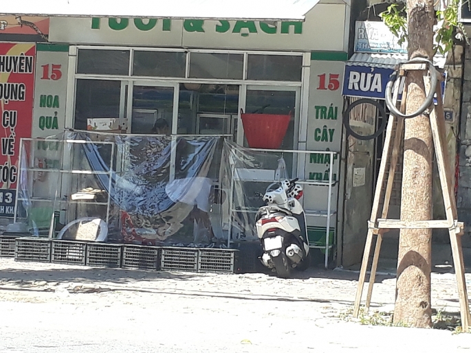 Hình ảnh một hộ kinh doanh trên đường Lê Hồng Phong mở cửa nhưng che chắn bằng bạt ni lon hết sức chắc chắn để phòng chống dịch
