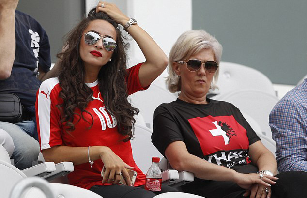 Nhưng bà Xhaka (phải) mặc chiếc áo với 1 phần là màu áo truyền thống của đội tuyển Thuỵ Sĩ, phần còn lại mang màu áo truyền thống của đội tuyển Albania, để ủng hộ cả 2 con