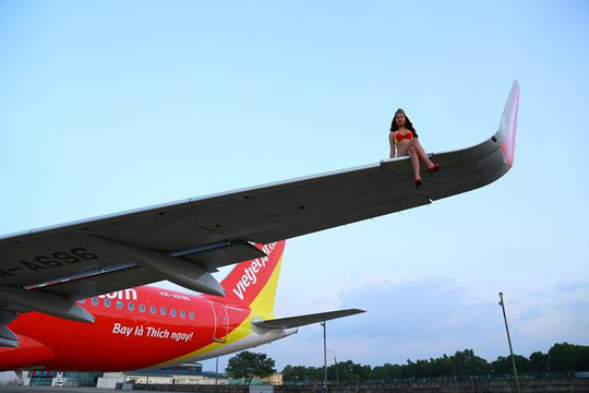Có người mẫu mặc bikini ngồi vắt vẻo trên cánh máy bay